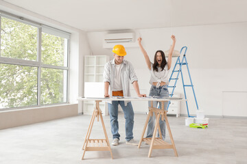 Naklejka premium Happy young woman with contractor planning repair in room