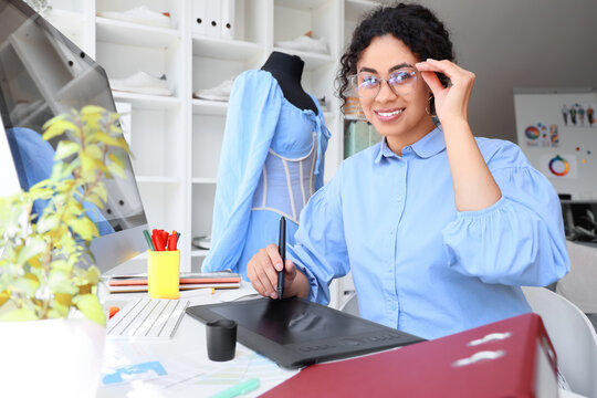 Female African-American graphic designer working with tablet at table in office
