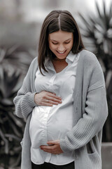 Portrait of a happy pregnant girl with a radiant smile, gently holding her belly. Ideal for showcasing the beauty of motherhood, pregnancy journeys, and family-related themes.