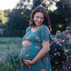 Portrait of a happy pregnant girl with a radiant smile, gently holding her belly. Ideal for showcasing the beauty of motherhood, pregnancy journeys, and family-related themes.