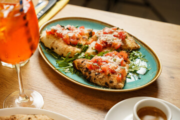Slices of bruschetta with tomato, salad and parmesan cheese at a restaurant