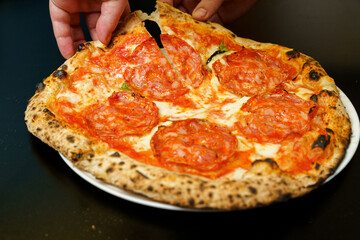 Taking a slice of salami and cheese pizza at an Italian restaurant