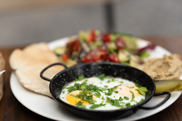 Turkish eggs chilbir with yogurt, fragrant butter, pea sprouts, flatbread and tea. Traditional Turkish breakfast with poached eggs with liquid yolk . Selective focus, close-up.