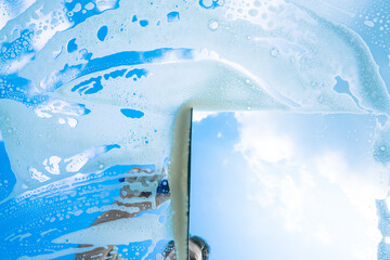 Fenster putzen mit Schaum und Abzieher / Fensterputzer bei der Arbeit