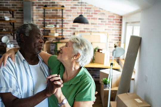 Happy senior couple dancing after moving into new home