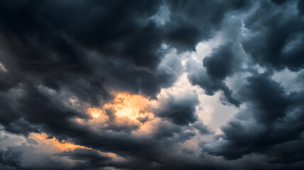 Obraz premium dark dramatic sky with black stormy clouds before rain or snow as abstract background, extreme weather, the sun shines through the clouds, high contrast photo