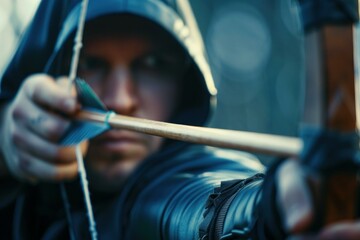 Archer wearing a hood aiming at target with bow and arrow