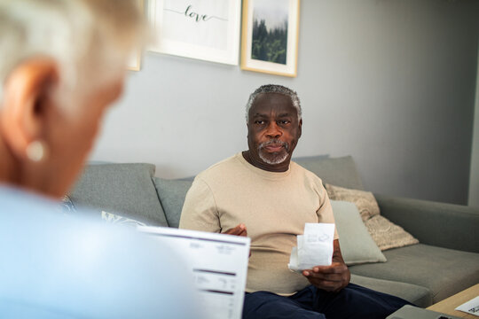 Diverse senior couple reading bills on the couch at home