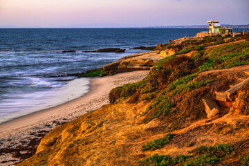 2023-12-31 ROCKY LA JOLLA SHORE WITH VEGETATION AND A SNADY BEASH WITH A LIFEGUARD STATION NEAR SAN...