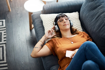Music, phone and headphones with woman in living room for streaming, playlist and podcast audio. Sound, technology and calm with above person at home for happiness, mindfulness and connection