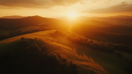 Naklejka premium Golden Sunset over Rolling Hills and Forested Landscape
