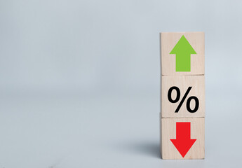 Staked wooden cube blocks with percentage symbol, green arrow up, and red arrow down icons. Interest rate financial and mortgage rates concept. Loan mortgage, VAT, tax, sale price. Stock investment..