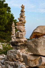 Obraz premium Stone cairns are balancing precariously on a rocky beach shore with pine trees in the background
