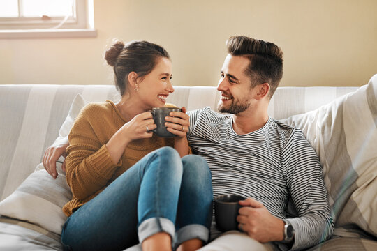 Relax, coffee or happy couple laughing on sofa with smile or love in house for care, latte and bonding. Apartment, break and people drinking tea beverage on couch together to chill in lounge in Spain
