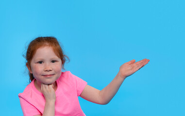 Young Girl in a Pink Shirt Posing Playfully Against a Bright Blue Background, Beaming With Joy