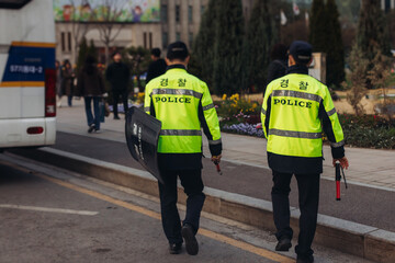 Korean police squad formation in protective uniform with "Police" logo, policemen patrol maintain public during political demonstration protest rally in the streets of Seoul city center, South Korea