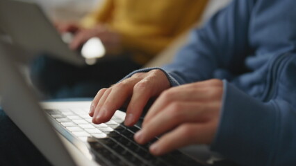 Closeup man fingers working laptop at apartment. Smiling woman looking husband