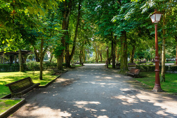 Walk with wooden benches and full of greenery in the park of the city of Lugo, Galicia.