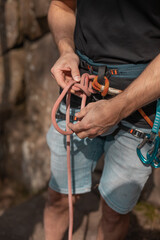 Man making a safety knot before climbing outdoors