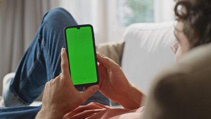 User scrolling chroma key smartphone at sofa closeup. Man hands holding device