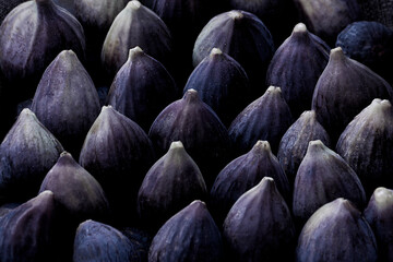 Fresh deep purple blue figs in future dusk color of the year 2025 are laid out in rows, creating a natural ornamental pattern. © Tatiana