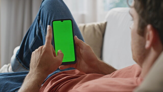 Guy hand swiping mockup screen mobile phone laying couch at apartment closeup