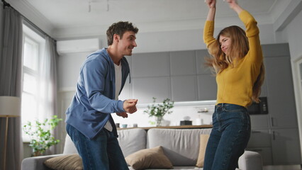 Fototapeta premium Carefree lovers dancing together at home. Happy romantic husband wife having fun