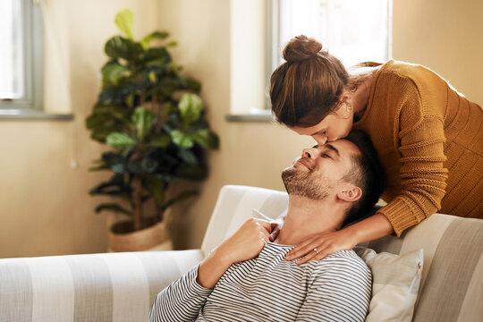 Sofa, couple and kiss on forehead for love, affection and bonding together in marriage at home. Happy people, woman and man with romance embrace for admiration, commitment and connection for support