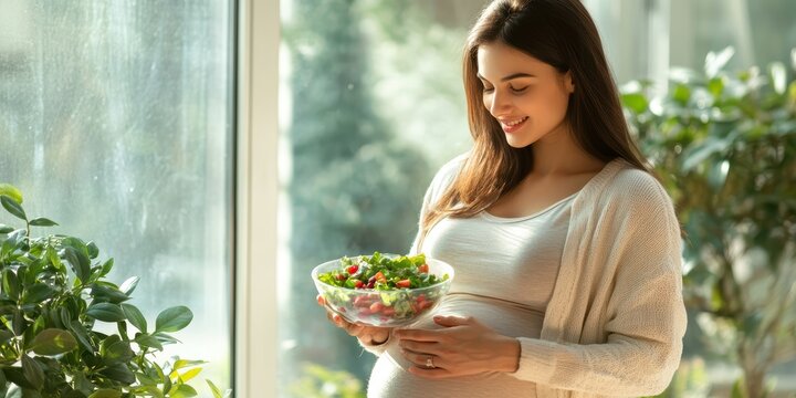 A serene pregnant woman holding a fresh salad bowl by a sunlit window, embracing a healthy lifestyle during pregnancy.