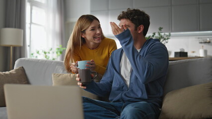 Happy lovers calling laptop drinking coffee at home. Family talking computer