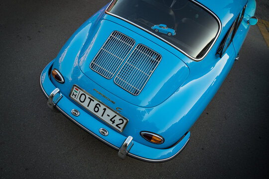 Porsche 356 from 1964. Engine hood with two grilles, rear lights and nameplate Porsche C. Scale diecast model copy (toy car) on its parcel shelf (rear deck). Subotica, 29.06.2024