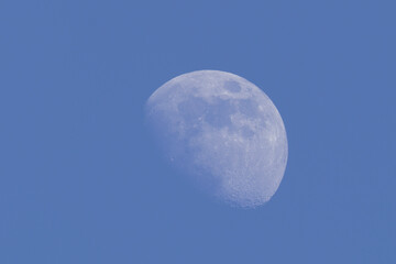Image of full moon in daytime blue sky.