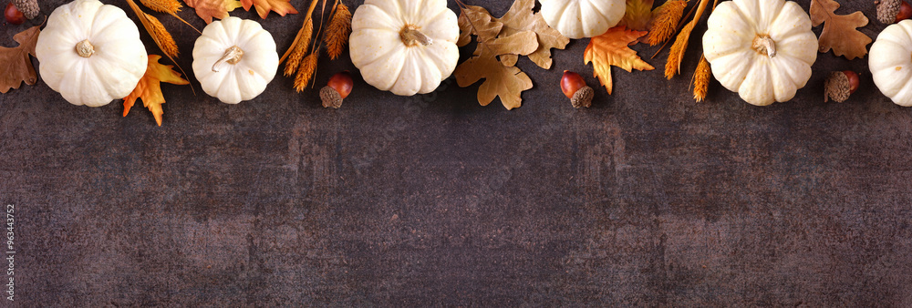 Poster fall top border of white pumpkins with muted orange and brown autumn decor. above view on a rustic d
