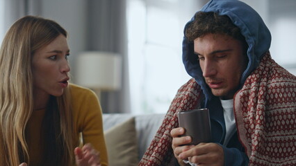Concerned woman caring sick husband at home closeup. Guy drinking hot beverage