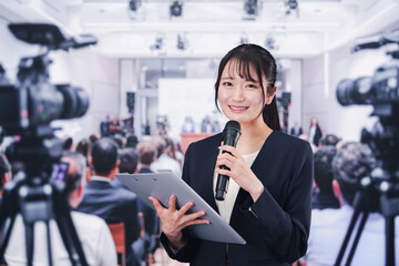 記者会見場からレポートをする女性記者