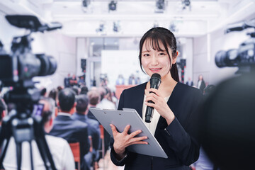 記者会見場からレポートをする女性記者