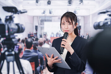Fototapeta premium 記者会見場からレポートをする女性記者