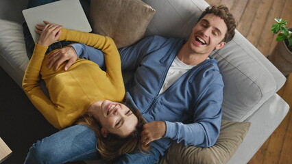 Laughing sweethearts relaxing sofa at new house top view closeup. Pair enjoying