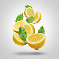 Fresh juicy lemons and green leaves falling on grey background