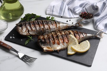 Delicious grilled mackerel, parsley, spices and lemon on white table