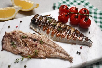 Board with delicious grilled mackerel, tomatoes and spices on table, closeup