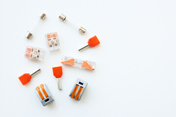Electrical wiring cable components, fuses, terminals, wire splice connectors isolated on white background. Electrician workshop table with parts for industry machinery. Banner with copy space.