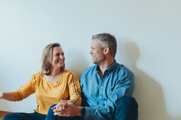 A happy couple is having fun at home while sitting on the floor.