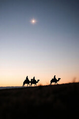 Epiphany Eve poster. Silhouette of the three wise men through the desert under the star of Bethlehem.
