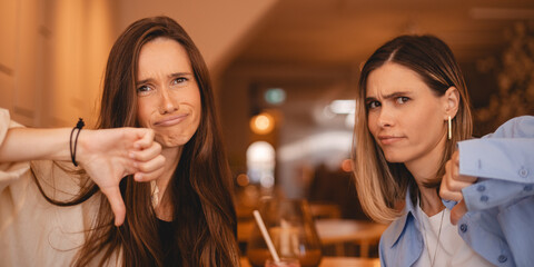 Two unhappy sisters friends women condemns with sign of dislike. Girls expressing discontent with...