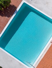 Fototapeta premium An aerial view of a pristine swimming pool with clear, blue water, showcasing a relaxing and luxurious ambiance. This image symbolizes tranquility, leisure, summer, and a vacation retreat.