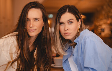 Two curious spying women friends sisters sitting in cafe restaurant, look at camera with jealousy,...