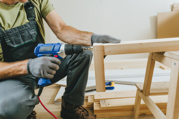 Close up of carpenter drilling a board with a screwdriver in his workshop