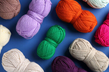 Different colorful yarns on blue background, flat lay