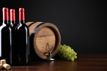 Corkscrew with metal handle, corks, grapes, bottles of wine and barrel on wooden table. Space for text
